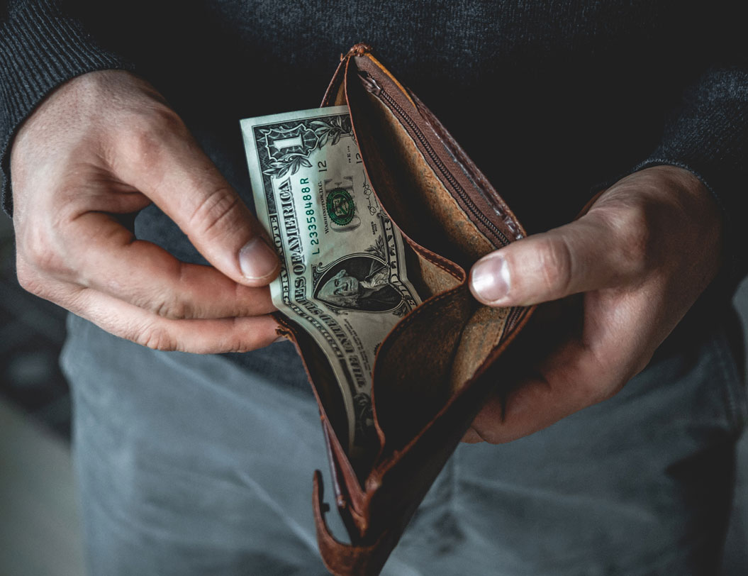 Man holding open wallet with $1 bill inside