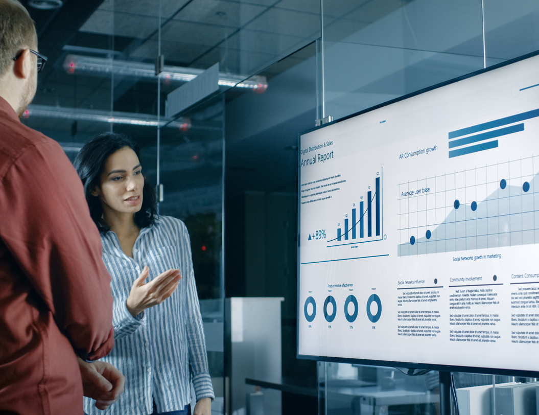 two business people looking at an annual report projection on screen