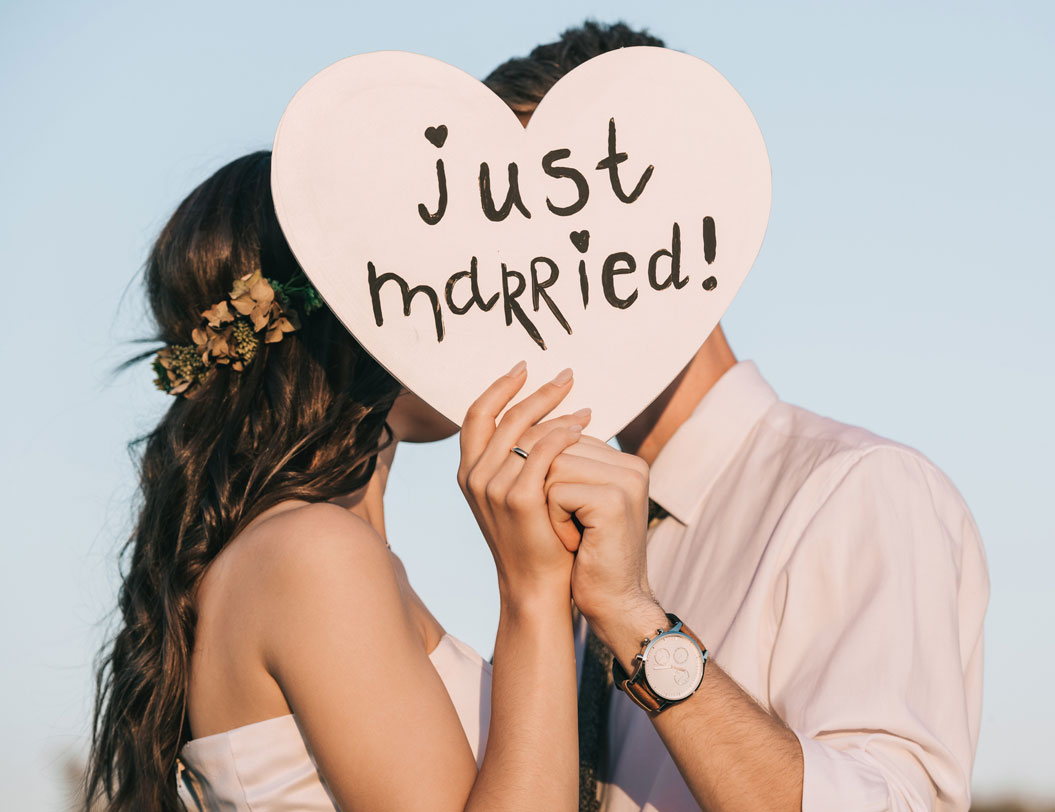 Newly married couple holding a heart-shaped sign saying "Just Married"