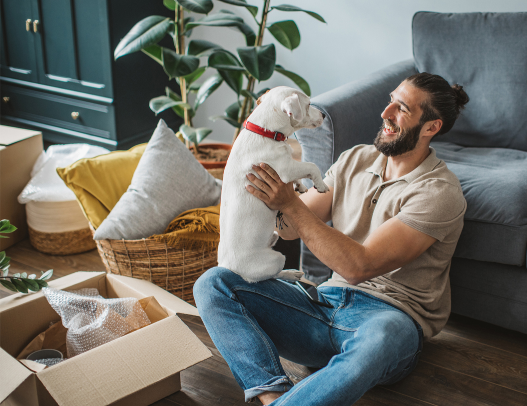 Man sitting on living room floor holding dog.