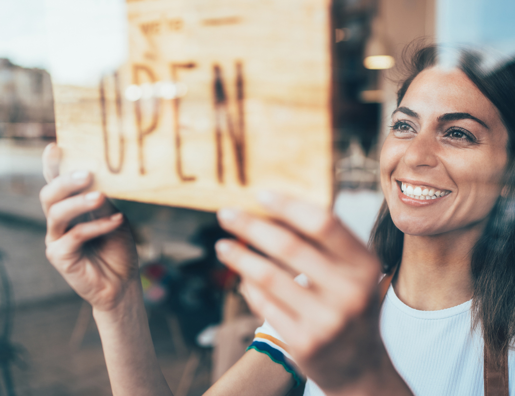 Woman hanging Open sign on business door