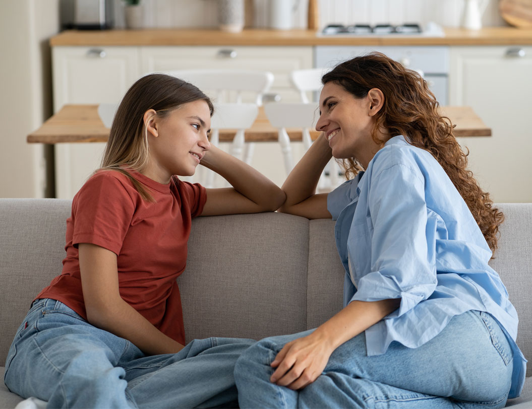 Mother and daughter sitting on the couch talking