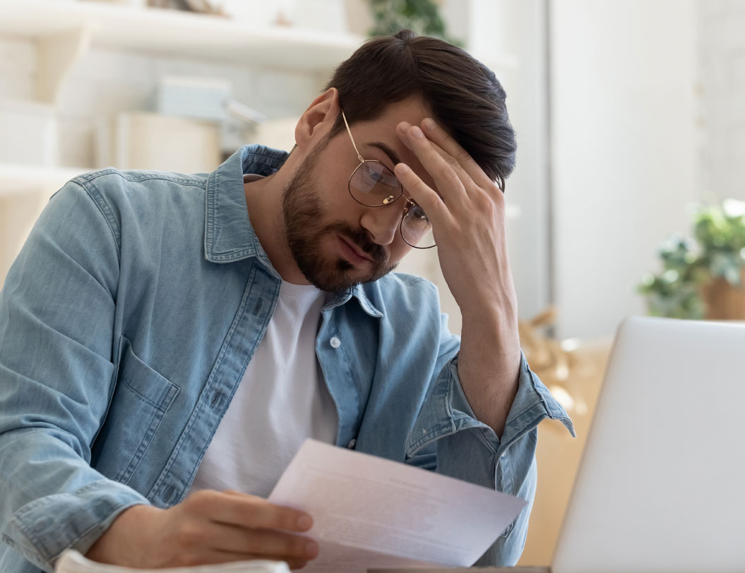 Man reviewing bill with hand on forehead