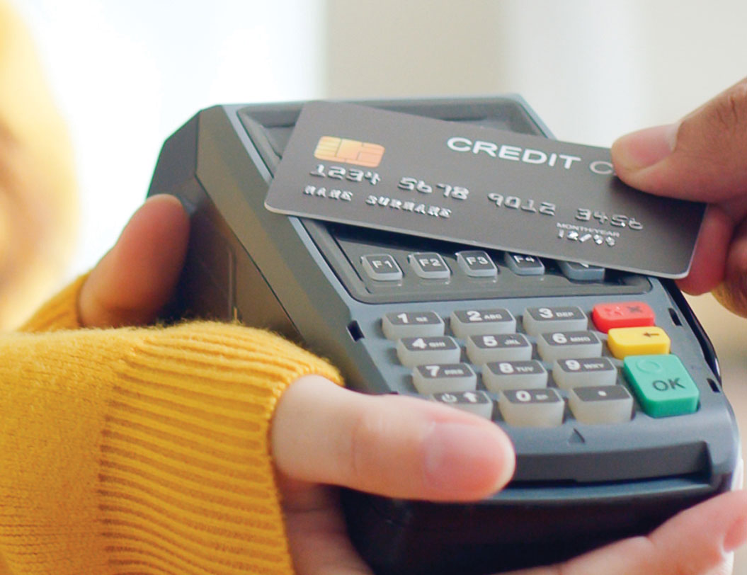 female holding credit card machine will person taps their card for purchase