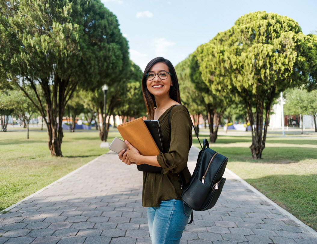 girl with books standing on college campus 