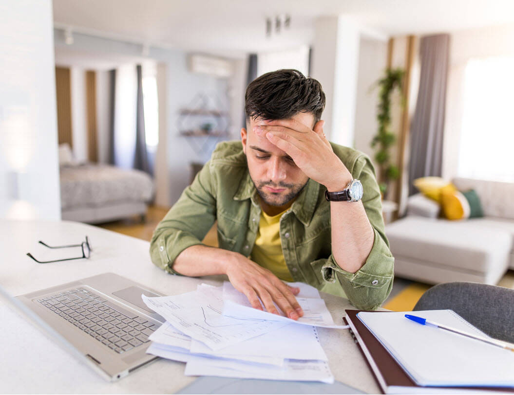 Man looking at paperwork with laptop