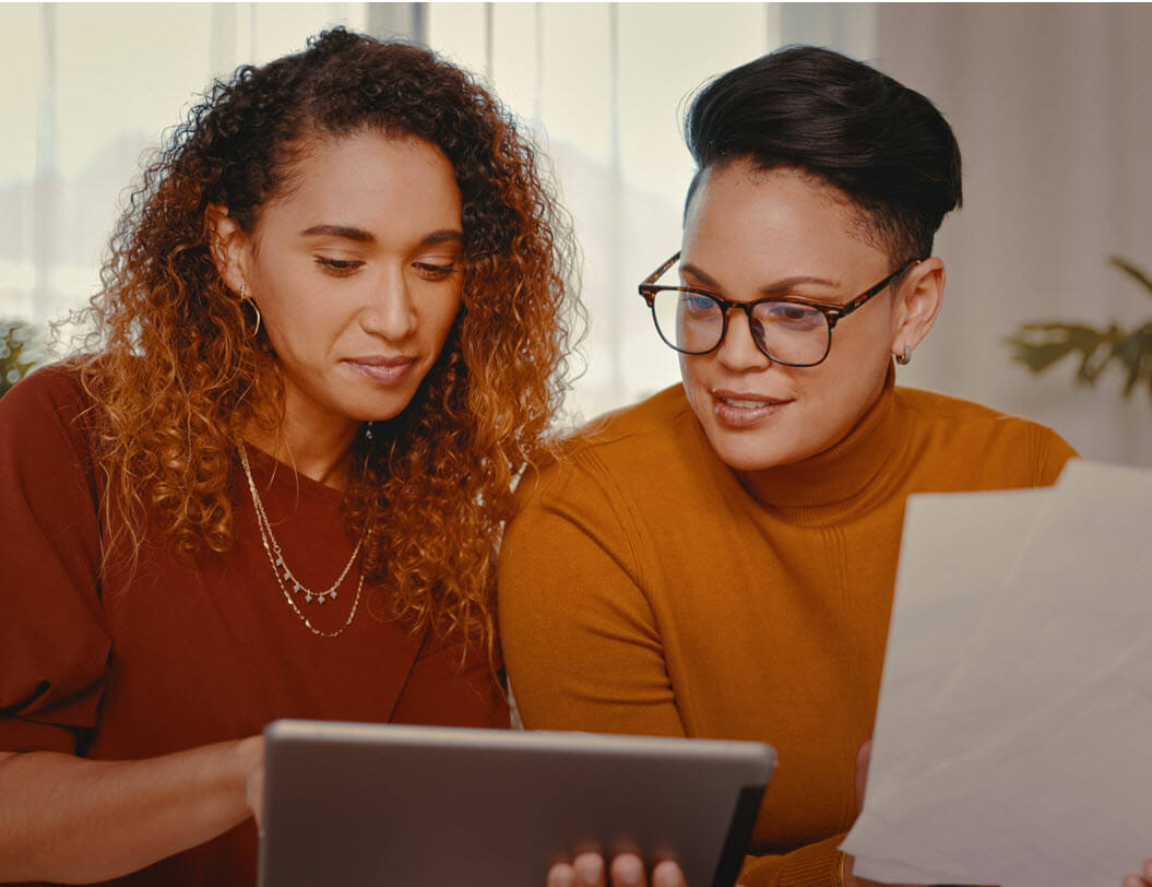 two women sitting at a computer, looking at their finances